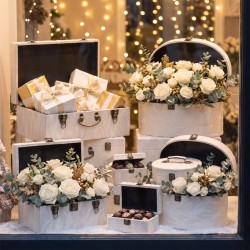 Vitrine de Noël avec malles et valises en tissu blanc garnies de fleurs – grossiste en coffrets cadeaux